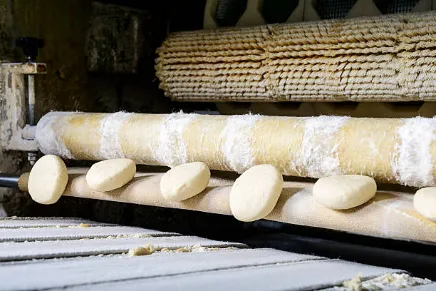 porciones de masa de pan a la salida de maquina boleadora
